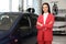 Young saleswoman near car in dealership