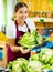 Young saleswoman proposing cauliflower, offering vegetables in supermarket