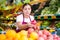 Young saleswoman proposing pomegranate, offering fruits in supermarket