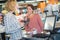 Young saleswoman scanning product at checkout counter in store