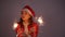 Young santa claus woman in red christmas or new year coat and hat holding sparkler