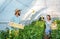 Young satisfied family couple picking pepper in the baskets in the greenhouse and smiling for vegetables they planted as small bus