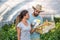 Young satisfied family couple picking pepper in the baskets in the greenhouse and smiling for vegetables they planted as small bus