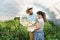 Young satisfied family couple picking pepper in the baskets in the greenhouse and smiling for vegetables they planted as small bus