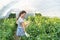 Young satisfied woman picking pepper in the basket in the greenhouse and smiling for vegetables she planted as small business star