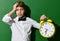 Young school boy hold big yellow time alarm on green