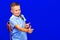 Young schoolboy in blue t shirt backpack pointing fingers hands on workspace isolated on blue background
