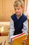 Young schoolboy packs books Behind a school desk