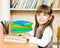 Young schoolgirl reading a book. looking at camera