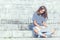 Young schoolgirl sitting on stairs with laptop and watching internet or social network