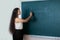 A young schoolgirl writes on the blackboard the first of September