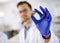 Young scientist hold a mineral specimen in protective glove at material science lab