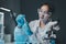 Young scientists in sterile clothing and safety goggles sitting at table conducting research investigations in a medical