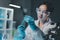 Young scientists in sterile clothing and safety goggles sitting at table conducting research investigations in a medical