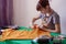 A young seamstress cuts out a mask pattern with scissors.