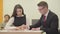 The young secretary sitting with her boss in the office. The man correcting the report of the girl. Office life