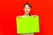 Young self-satisfied teenager girl holding blank paper sheet over red background