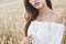 Young sensitive girl in white dress posing in a field of golden wheat