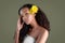 Young sensual african american woman with artistic make-up and gerbera in hair isolated on greu background. Yellow flowers in hair