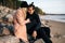 Young sensual couple in love sitting on stones at the beach, hugging and enjoy each other. A