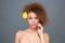 Young sensual curly woman with yellow flower in her hair
