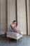 Young serene ballet dancer girl sits on ottoman gracefully securing ribbons of pointe shoes