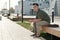 Young serene businessman sitting on bench in the street