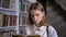 Young serious girl is reading book, library on background
