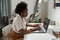 Young serious home office manager sitting by desk in front of laptop