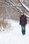 Young serious man in jeans walk in forest at winter