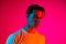 Young serious man posing isolated on magenta studio background in neon light, Concept of human emotions, facial