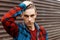 Young serious man with a stylish hairstyle in a trendy t-shirt in a fashionable plaid shirt poses near a vintage metal wall