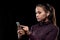 Young serious sportswoman with cordless earphones scrolling in smartphone