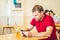 Young serious thoughtful pensive attentive man tense thinking send message by smart phone in red shirt in cafe drinking