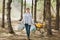 Young serious woman in casual clothes holding trash bags cleaning rubbish in littered park or forest. Problem of