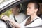 Young serious woman driving a car, man sitting aside