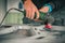 Young service man is using an angle grinder with a wire brush to clean the underside of an old vintage car about to be restored