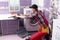 young serviceman checks broken washing machine loader on floor in room closeup