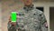 Young serviceman showing smartphone green screen, army support app, gadget