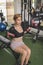 A young and sexy asian woman does seated dumbbell bicep curls on a flat bench at the gym. Wearing a black crop top and bike shorts