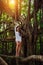 Young sexy barefoot girl in short white dress poses on big banyan tree.  Long-legged brunette stands among the branches of a huge