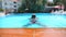 Young sexy girl swimming across pool of luxury hotel. Attractive tanned woman refreshing in basin during summer travel