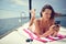 A young sexy girl is using a smartphone while is enjoying a sunbath on a yacht. Summer, sea, vacation
