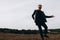 Young sexy man in leather jacket and sunglasses dancing outdoor. Silhouette against grey sky