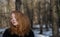Young sexy woman with red hair and head down, with black clothes, is standing sad, depressed, desperate in winter
