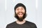 Young shaggy funny happy guy with long beard in hat laughing with open mouth