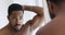 Young shirtless african ethnicity man styling hair with fingers.