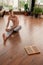 Young shirtless and barefoot sportsman in grey pants exercising on the floor