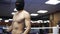 Young shirtless boxer in black thief mask standing on the boxing ring breathing deeply to calm his nerves, preparing