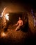 Young shirtless male in a cave with a flame torch looking at the walls